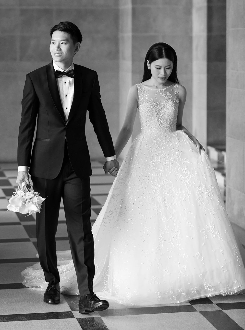 Groom in a black tuxedo walking with his bride